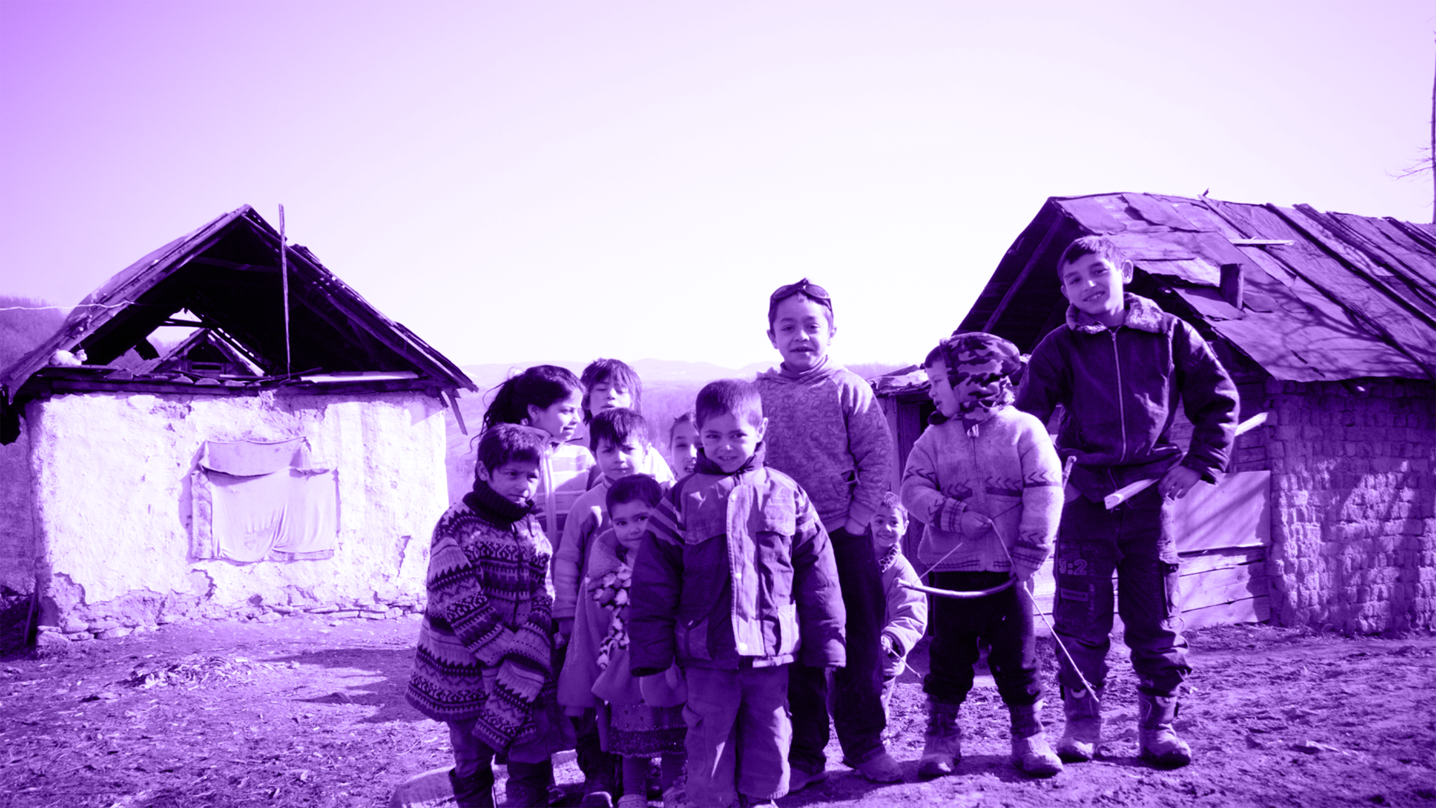 Children standing together outside stone houses